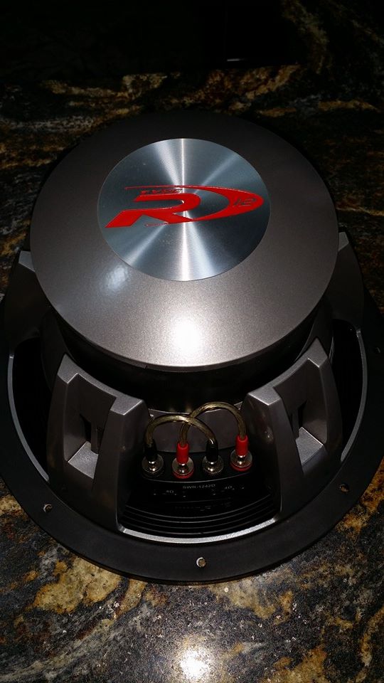 Overhead view of an Alpine subwoofer with red and silver logo.