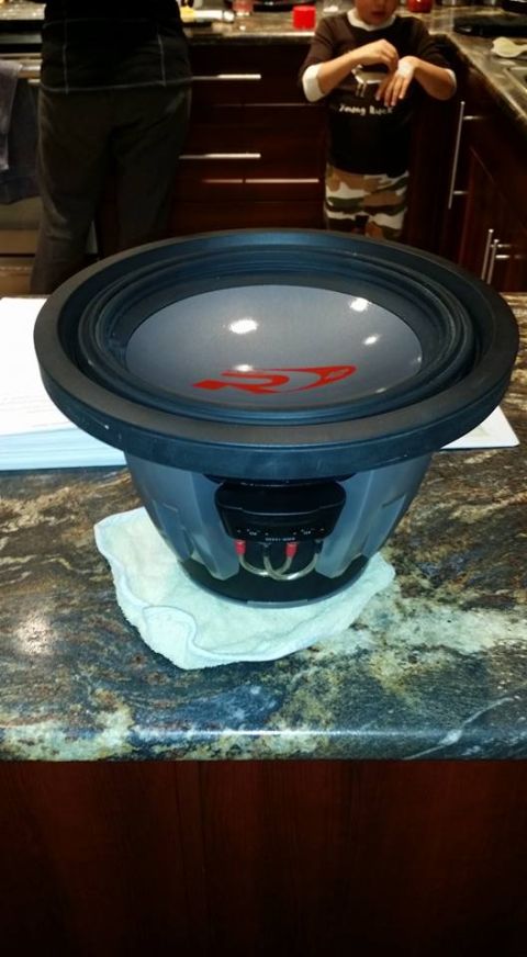 1984 Ford Bronco - A large Alpine subwoofer speaker rests on a granite countertop, placed on a white towel. The speaker has a gray cone with a red Alpine logo.
