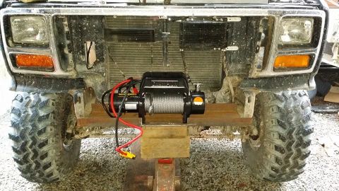1984 Ford Bronco - Front view of a dirty, modified Ford Bronco with a winch mounted to a custom bumper. The vehicle has large off-road tires and the grille an…