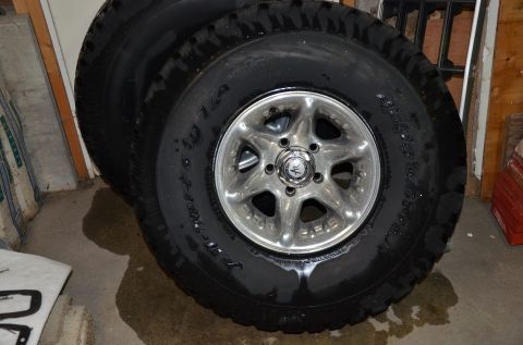 1984 Ford Bronco - Close-up of tires and chrome wheels, with visible text on the tire sidewall.