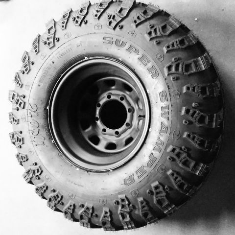 1984 Ford Bronco - A close-up view of a Super Swamper tire mounted on a steel wheel, highlighting its tread design.