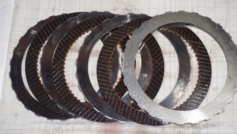 1984 Ford Bronco - Several transmission clutch plates are laid out on a surface, showing their metallic rings and friction material.