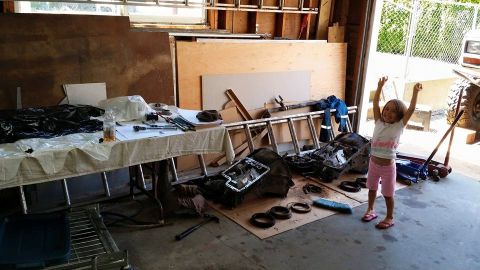 1984 Ford Bronco - A young girl celebrates in a garage filled with transmission parts and tools.