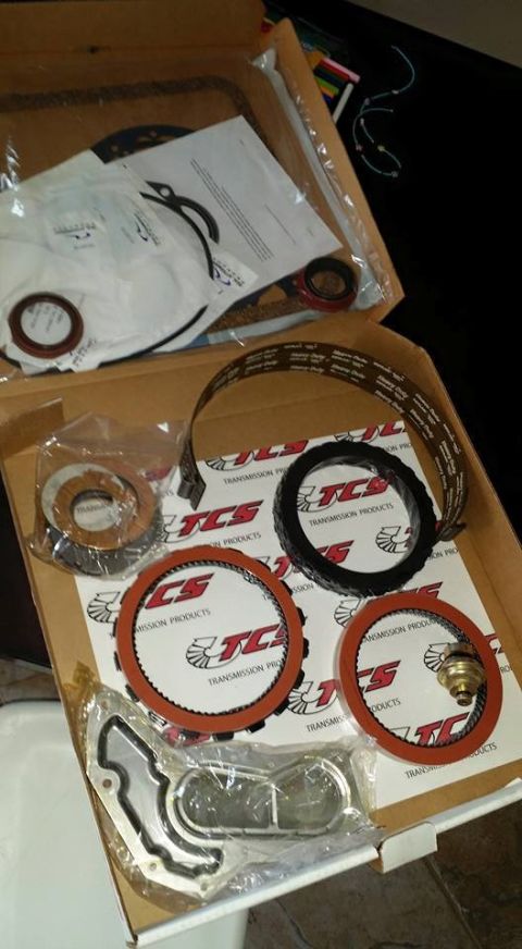 1984 Ford Bronco - Various transmission parts, including gaskets and clutch plates, are laid out in a box.