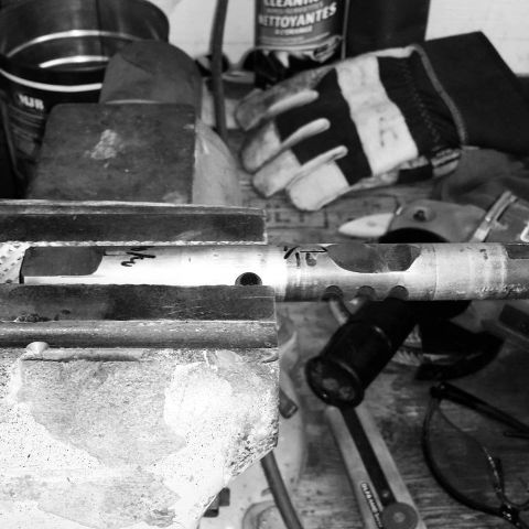1984 Ford Bronco - Tools and a metal part are laid out on a workbench, suggesting a repair or fabrication project.