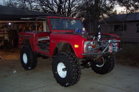 1974 Ford Bronco - A red 1974 Ford Bronco is modified for off-road use with large tires and a custom bumper.