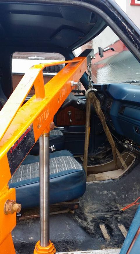 1984 Ford Bronco - Interior view of a vehicle with an engine hoist, showing blue seats and dashboard details.