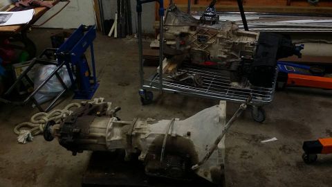 1984 Ford Bronco - Two transmissions are visible in a workshop setting, one in the foreground and another on a cart in the background.