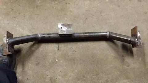 1984 Ford Bronco - A fabricated metal crossbar with mounting plates is shown on a concrete surface.
