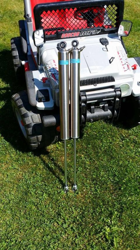 1984 Ford Bronco - A toy jeep is parked on grass with two shock absorbers in front of it.