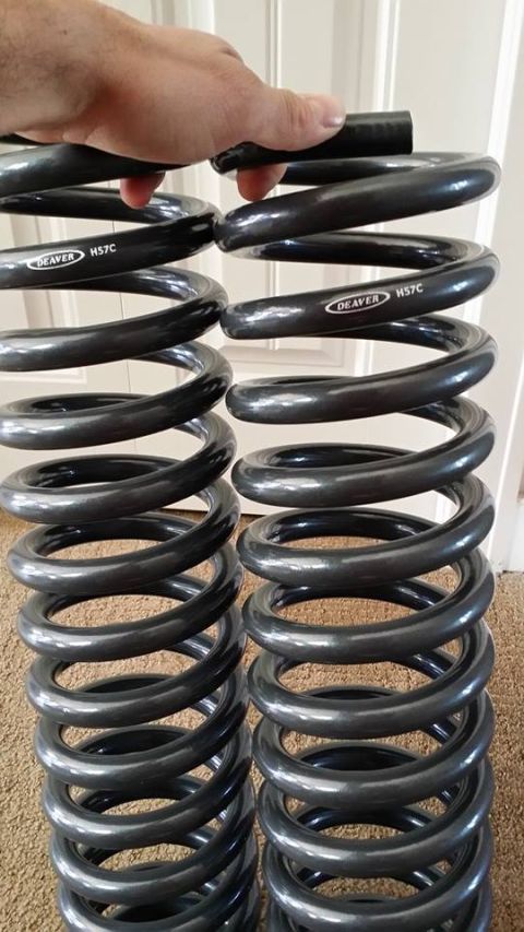 1984 Ford Bronco - A pair of Deaver H57C suspension coil springs are shown, with a hand holding a pipe above them.
