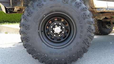 1984 Ford Bronco - A close-up view of a off-road tire and wheel assembly, highlighting its aggressive tread pattern and sturdy construction.