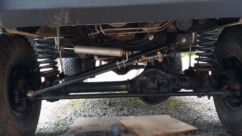 1984 Ford Bronco - Close-up of a vehicle's undercarriage, focusing on the front axle and suspension system.