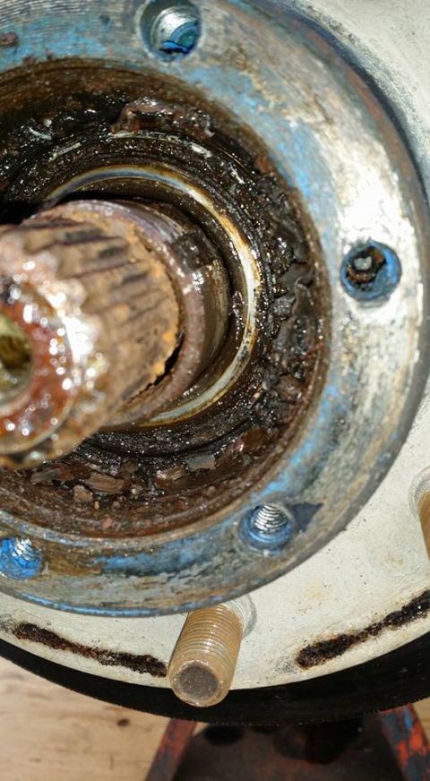 1984 Ford Bronco - Close-up of a heavily corroded wheel bearing assembly, showing a damaged spindle and old grease.