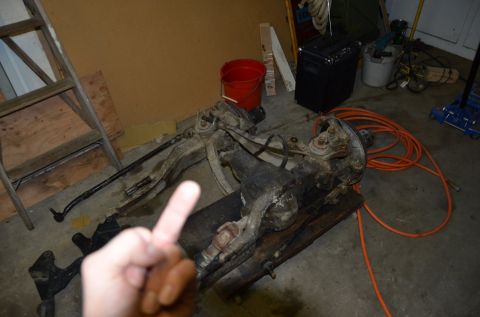 1984 Ford Bronco - Garage scene with disassembled front axle and suspension parts laid out.