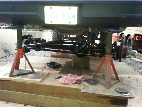 1984 Ford Bronco - Undercarriage of a vehicle, possibly a Ford Bronco, is supported by jack stands for maintenance, with a license plate in view.