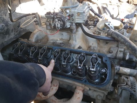1984 Ford Bronco - A hand points to the valve train of an engine, likely during maintenance or inspection.