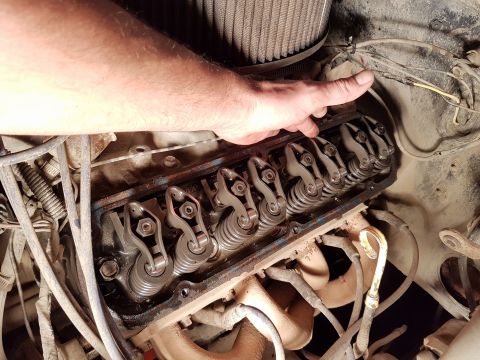1984 Ford Bronco - A hand points to the valve train components of an engine, likely during maintenance or inspection.