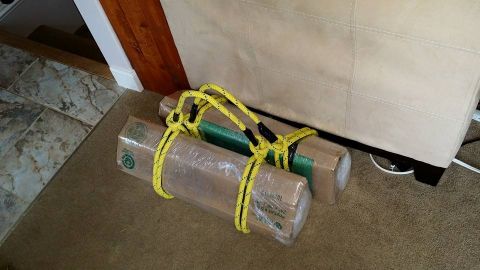1984 Ford Bronco - Two packages are secured with yellow rope and placed on a carpeted floor next to a piece of furniture.