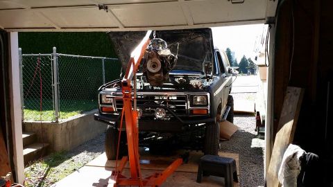 1984 Ford Bronco - A Ford Bronco is undergoing engine removal in a garage.