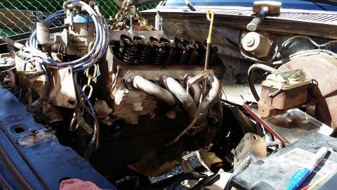 1984 Ford Bronco - Engine bay with V8 engine and exhaust manifold, possibly being worked on.