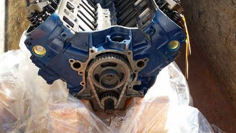 1984 Ford Bronco - Engine block with timing chain and gears visible, wrapped in plastic.