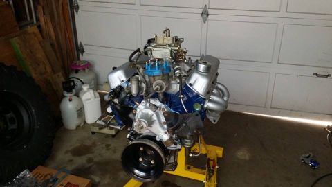 1984 Ford Bronco - A V8 engine is displayed on an engine stand in a garage setting, with various items in the background.
