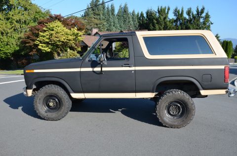 1984 Ford Bronco - This SUV, likely from the early 1980s, features a two-tone paint scheme with dark gray body and tan accents.
