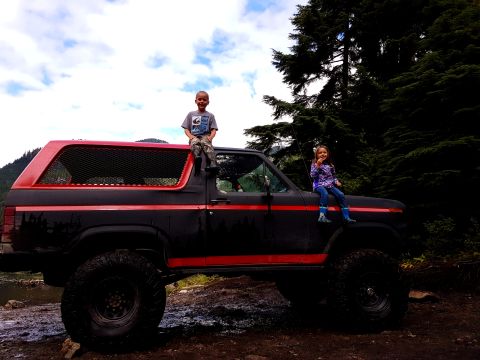 1984 Ford Bronco - Children pose on a lifted Ford Bronco in a wooded area.