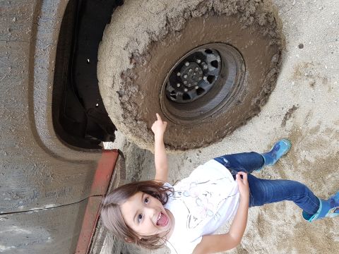 1984 Ford Bronco - A young child points at a massive, mud-covered tire, indicating a challenging off-road situation.