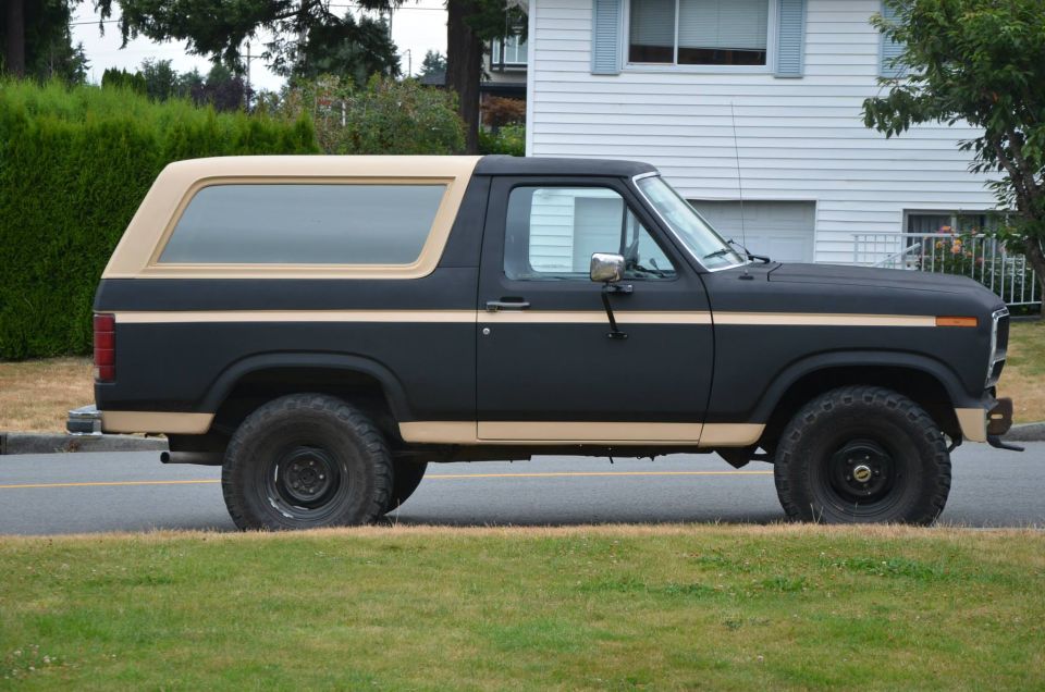 Side view of a black Ford Bronco with tan trim and a tan top
