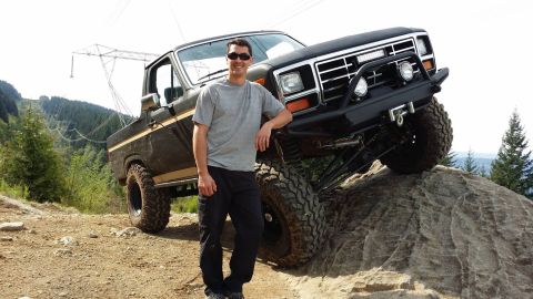 1984 Ford Bronco - Man poses with a lifted black 1980 Ford Bronco on a rocky off-road trail.