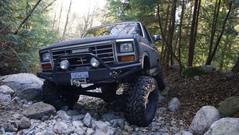 1984 Ford Bronco - This modified Ford Bronco is navigating a rocky trail in a wooded area.