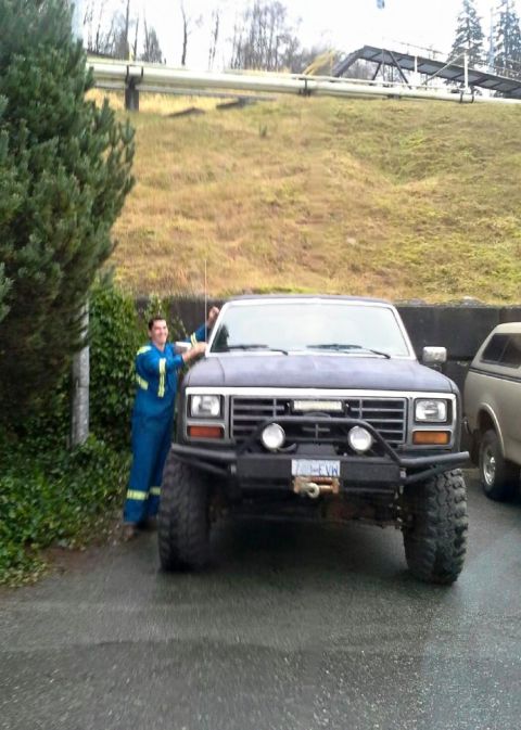 1984 Ford Bronco - Modified Ford Bronco with a custom front bumper and winch. A person in work clothes is standing next to it.