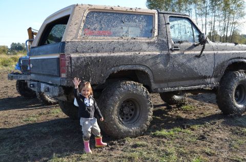 1984 Ford Bronco - Muddy Ford Bronco and a child enjoying an off-road adventure.