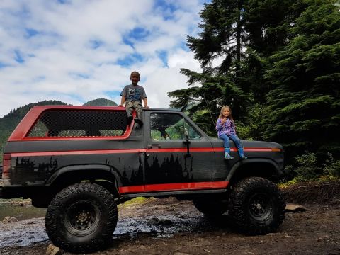 1984 Ford Bronco - Children pose on a black and red Ford Bronco parked in a wooded area.