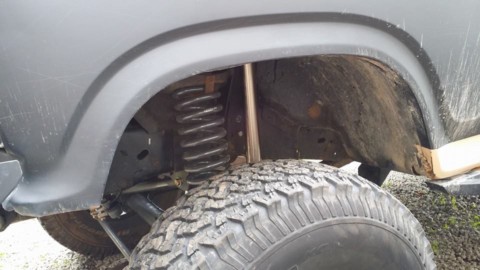 Close-up of a vehicle's rear wheel well showing the coil spring and shock absorber