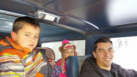1984 Ford Bronco - A man and two children are inside a vehicle, with the children in the foreground.
