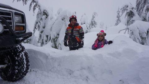 1984 Ford Bronco - Two children play in the snow next to a vehicle, which appears to be an older model SUV.