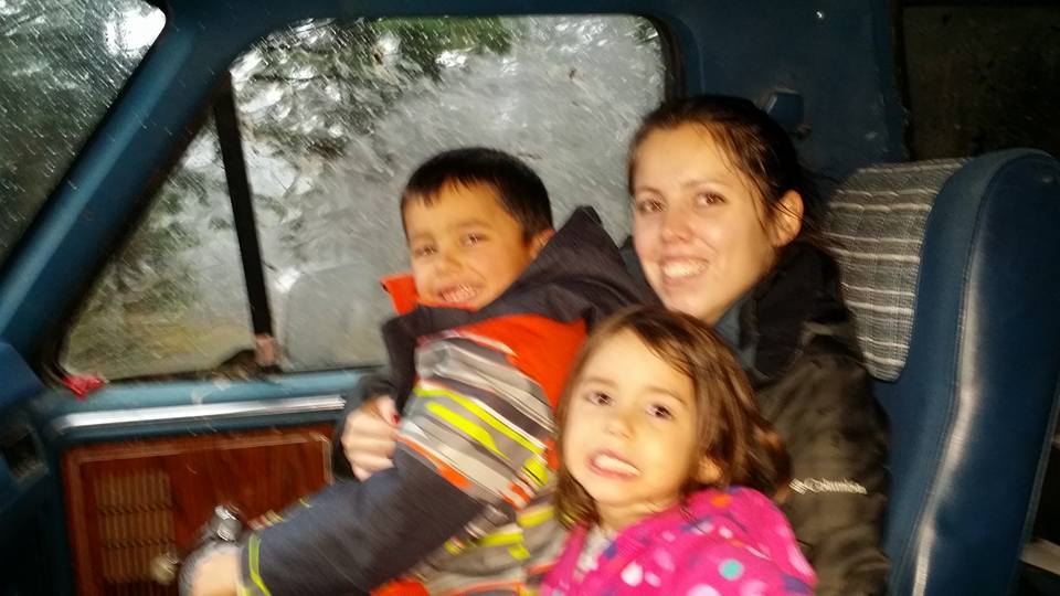 Woman and two children inside a vehicle, looking out the window