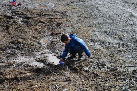 1984 Ford Bronco - A child enjoys playing in the mud with a toy car.