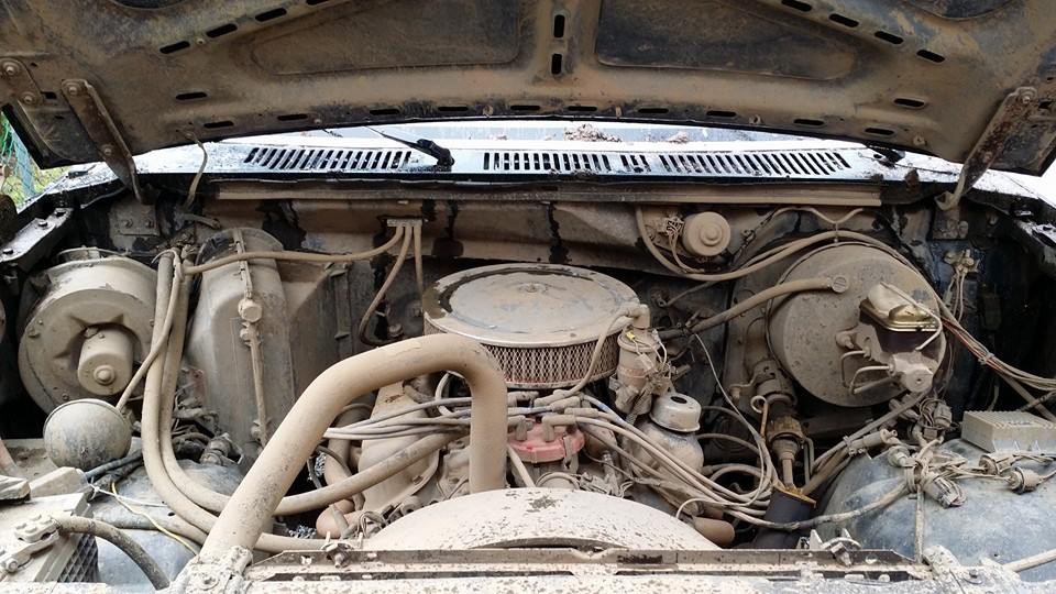 Engine bay of a dirty vehicle, showing engine components and wiring