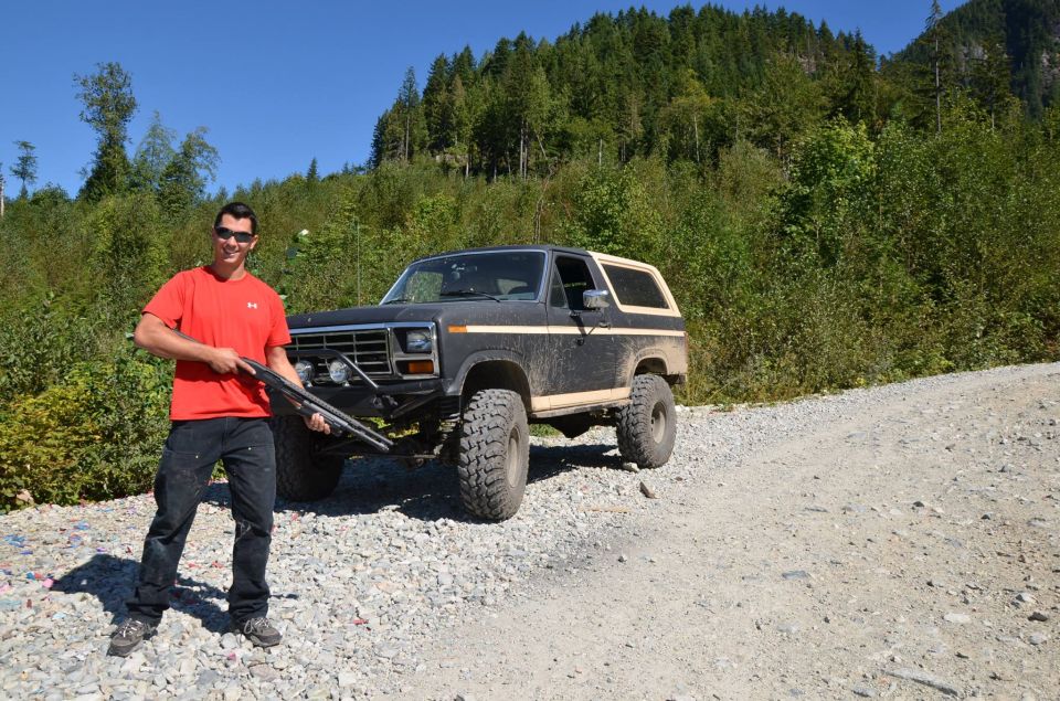 Dark brown Ford Bronco with beige trim and large tires parked on a gravel road