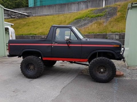 1984 Ford Bronco - This modified Ford Bronco features a lifted suspension and oversized tires, deviating from its original 1980s design.