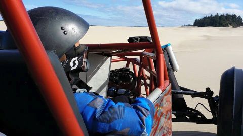 1984 Ford Bronco - View from inside a dune buggy as it travels across sandy terrain under a partly cloudy sky.