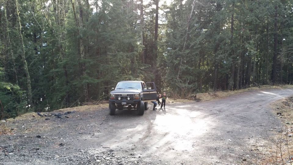 Black SUV with lifted suspension parked in forest, driver's door open