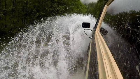 1984 Ford Bronco - Vehicle driving through a water crossing on a forest road.