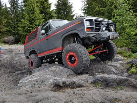1984 Ford Bronco - This heavily modified Ford Bronco is navigating a challenging rocky trail.