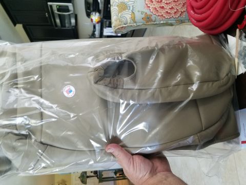1994 Ford Bronco - A hand holds a package of tan seat covers with a 'Made in USA' sticker visible.