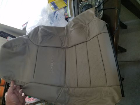 1994 Ford Bronco - A tan leather car seat, identified as Lariat trim, is held up for inspection.